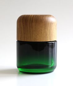 a green jar with a wooden lid on a white surface