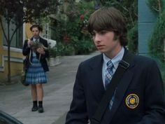 a young man in a suit and tie standing next to a woman on the sidewalk