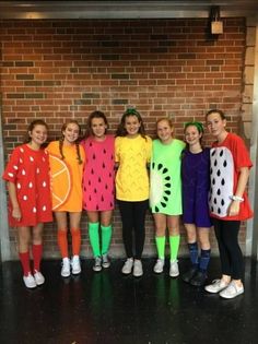 a group of young women standing next to each other in front of a brick wall