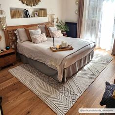 a large bed sitting on top of a wooden floor next to a window covered in curtains