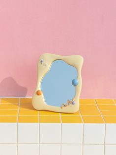 an odd shaped mirror sitting on top of a tiled counter next to a pink wall