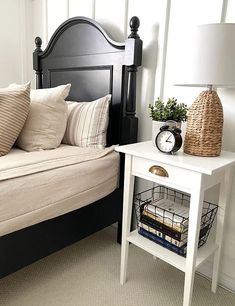 a bed sitting next to a night stand with a clock on it's side