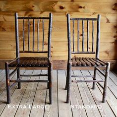 two wooden chairs sitting next to each other on top of a wooden floor in front of a wood wall