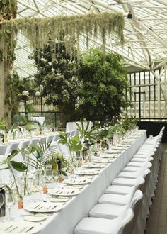 the long tables are set with white linens and place settings