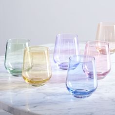 four different colored glasses sitting on top of a marble counter