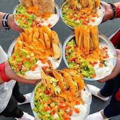 several people holding plates with tacos and burritos on them in the middle of a circle