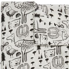 a black and white bed spread with animals on it's side, next to a pillow