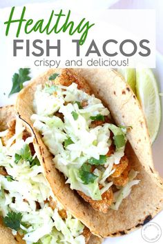 two fish tacos on a plate with lime wedges