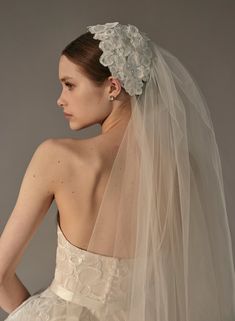 a woman in a wedding dress with a veil on her head and the back of her neck