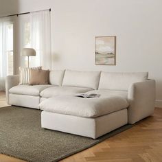 a living room with a large white sectional couch and rugs on the hardwood floor