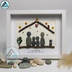 a white frame with some rocks and stones in front of it that has a family picture on it