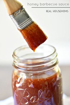 a wooden brush sticking out of a jar filled with honey barbecue sauce