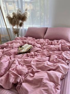 a pink comforter on a bed with a book laying on it's side