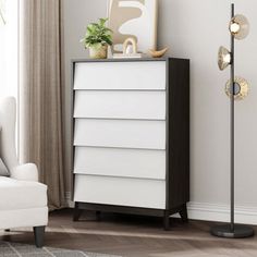 a living room with a white chair and a tall black lamp next to a dresser