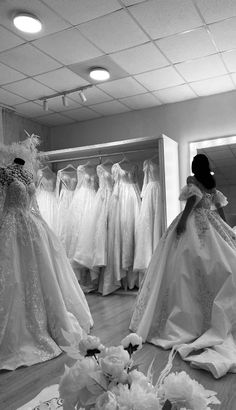 a woman looking at dresses on display in a dress shop with flowers and vases