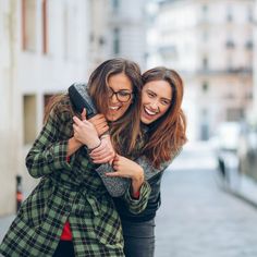 two women hugging each other on the street