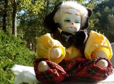 a stuffed animal doll sitting on top of a wooden table next to some grass and trees