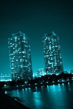 some very tall buildings by the water at night