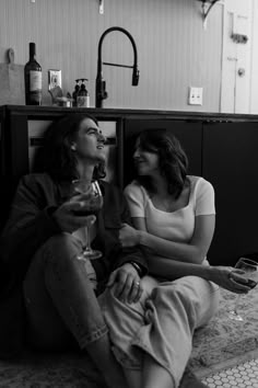 black and white photograph of two women sitting on the floor with wine glasses in their hands