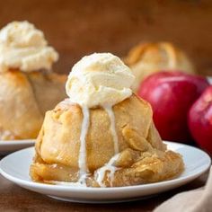 two small desserts are on white plates with apples in the background and one is drizzled with icing