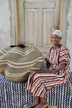 a woman sitting on top of a black and white checkered blanket next to a vase