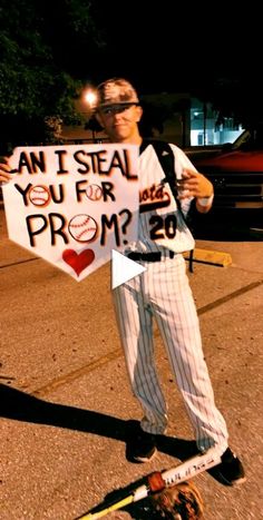 a baseball player holding up a sign that says can i steal you for prom?