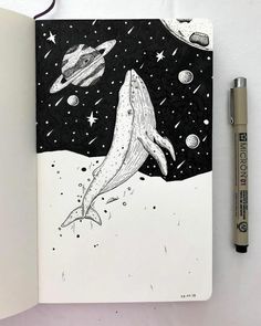 an open notebook with a drawing of a whale in space