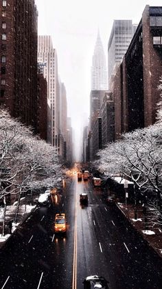 a city street filled with lots of traffic and tall buildings covered in snow on a cloudy day