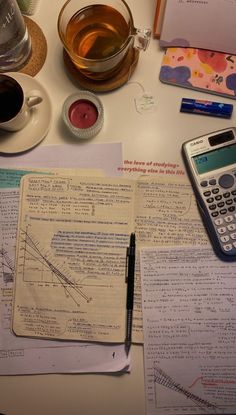 a table topped with papers and a calculator next to a cup of coffee