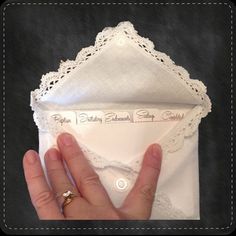 a hand is holding an envelope with lace on it