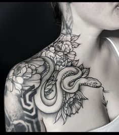 a woman's chest with a snake and flowers tattoo on her upper half sleeve