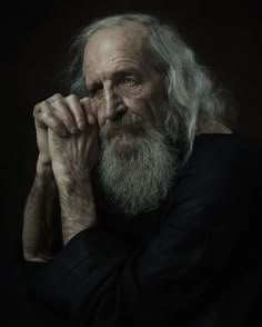 an old man with long white hair and a beard is posing for a photo in the dark