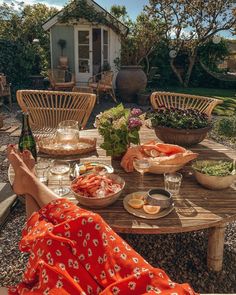 a person sitting at a table with food and drinks on it in front of a house