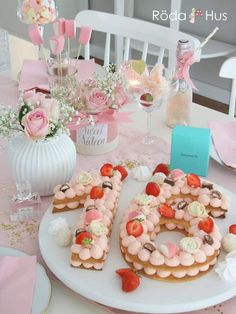 the table is decorated with pink and white flowers, cookies, and other items on it