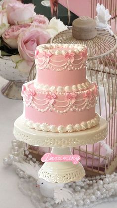 a three tiered cake sitting on top of a table next to a birdcage