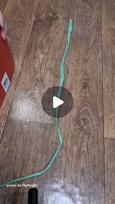 a person is cutting through the wood floor with a green tape and an electric cord