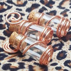 three wine corks are wrapped in copper wire and placed on a leopard print fabric