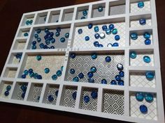 an assortment of blue and white glass beads in a display case on a wooden table