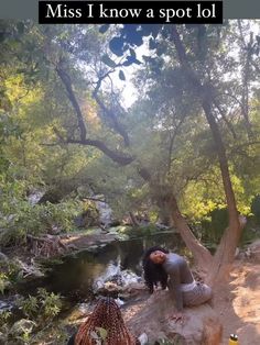 a woman sitting on top of a rock next to a river