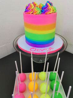 there is a cake with rainbow icing on the top and candy on the bottom