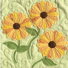 two yellow flowers are on the side of a quilted wall hanging ornament