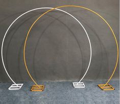 three circular metal sculptures with yellow and white lines on each one, standing in front of a gray wall