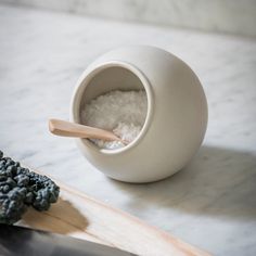 a knife and some seaweed on a cutting board next to a bowl with salt in it