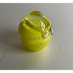 a yellow glass vase sitting on top of a white table next to a black object