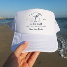 someone is holding up a white hat on the beach