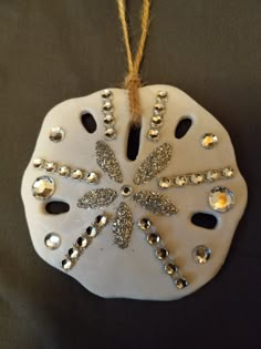 a white ornament hanging from a string on a black surface with gold and silver decorations