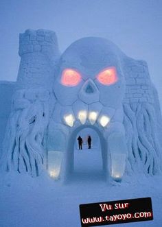 two people are standing in front of an ice sculpture with glowing eyes and large teeth