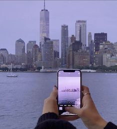 a person taking a photo with their cell phone in front of the cityscape