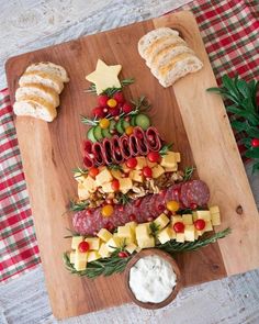 a christmas tree shaped platter with meats, cheese and fruit on it is ready to be served