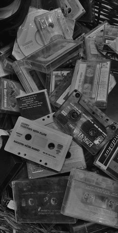 an old pile of cassettes and cds in black and white